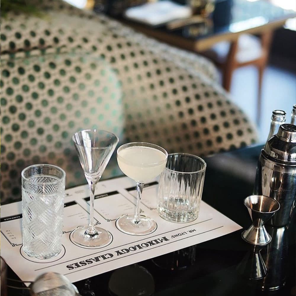 A selection of cocktail glasses and a shaker arranged on a bar mat.