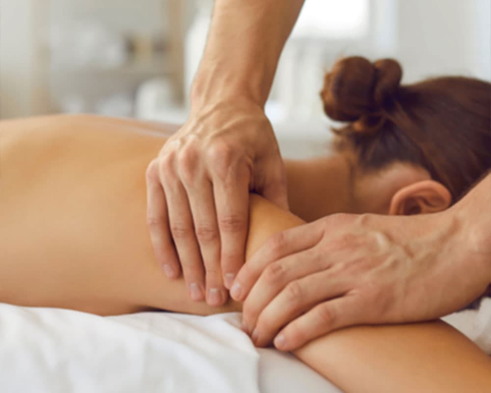 A person receives a shoulder massage in a serene setting.