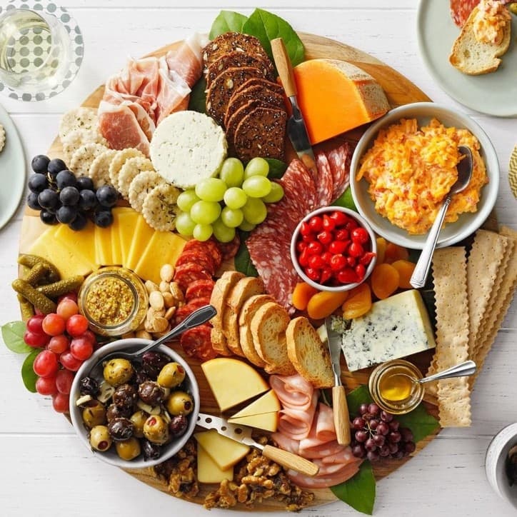 A vibrant charcuterie board featuring an assortment of meats, cheeses, fruits, crackers, and spreads.