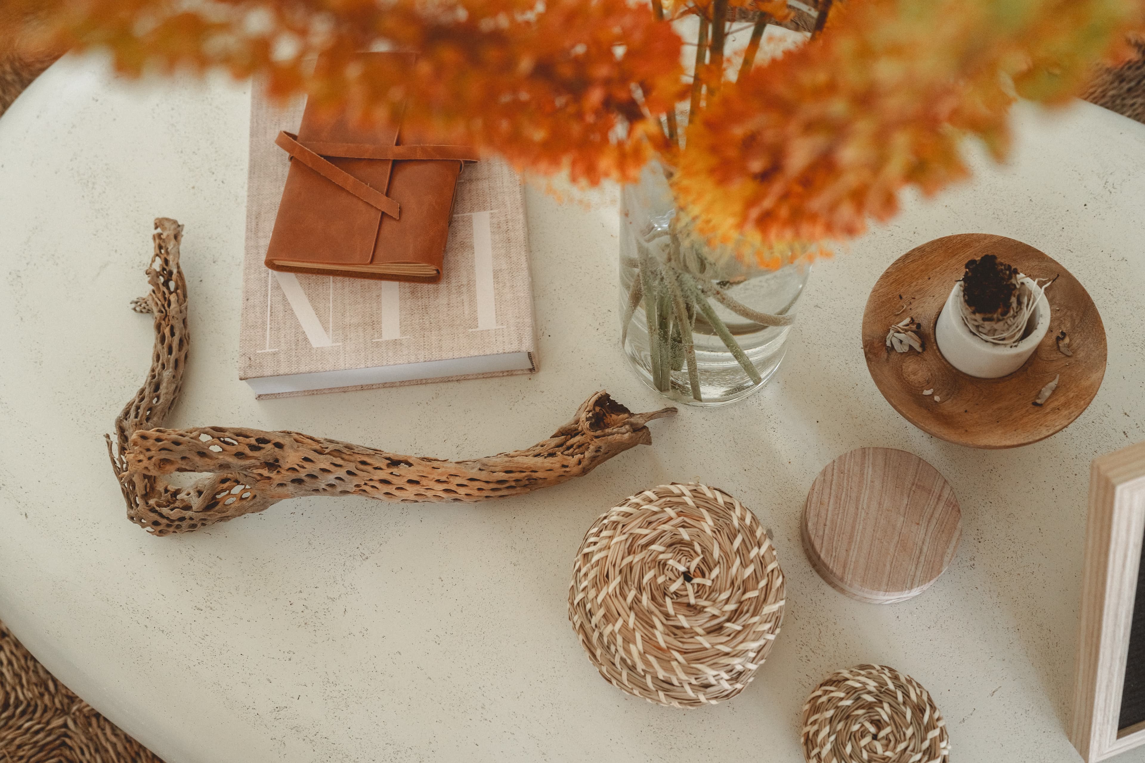 Flat lay of a coffee table with a vase of orange flowers, a notebook, and decorative items.
